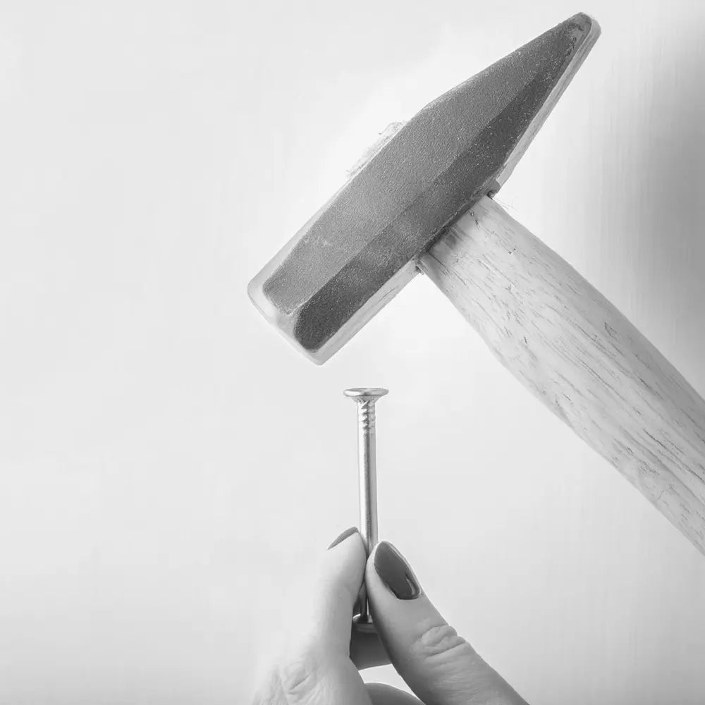 A woman holding a hammer and a nail